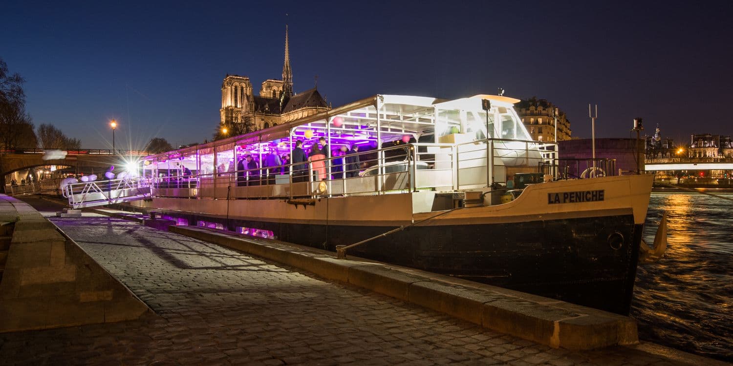 La Péniche | vue extérieure de nuit, lumière magenta sur la coque blanche